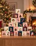 Patisserie Valerie advent calendar with 24 illustrated numbered boxes stacked into a tower in front of a Christmas tree and fireplace