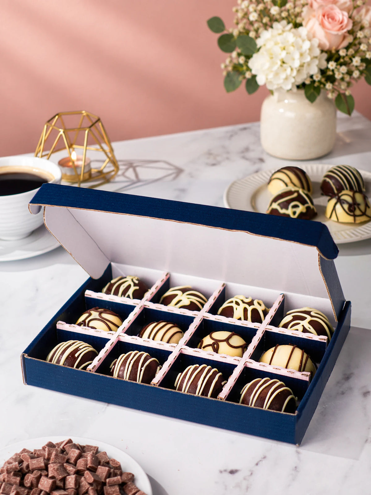 Assorted chocolate-coated cake bites arranged in an open Patisserie Valerie gift box