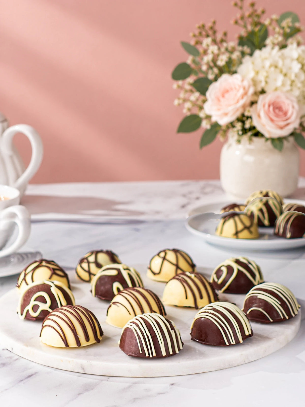 Assorted chocolate-coated cake bites on a round marble serving board by Patisserie Valerie