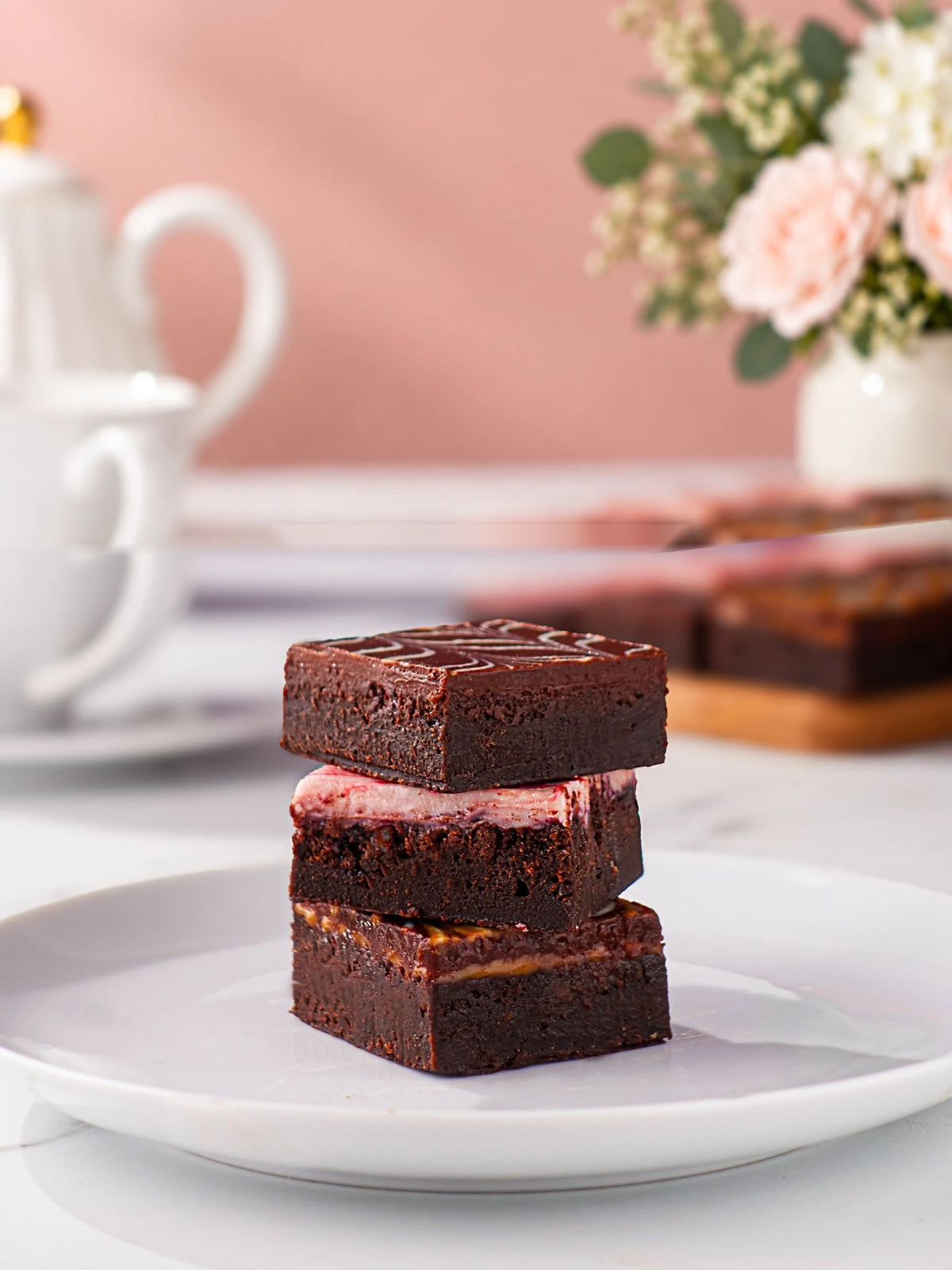 Three chocolate fudge brownies stacked on a white plate by Patisserie Valerie