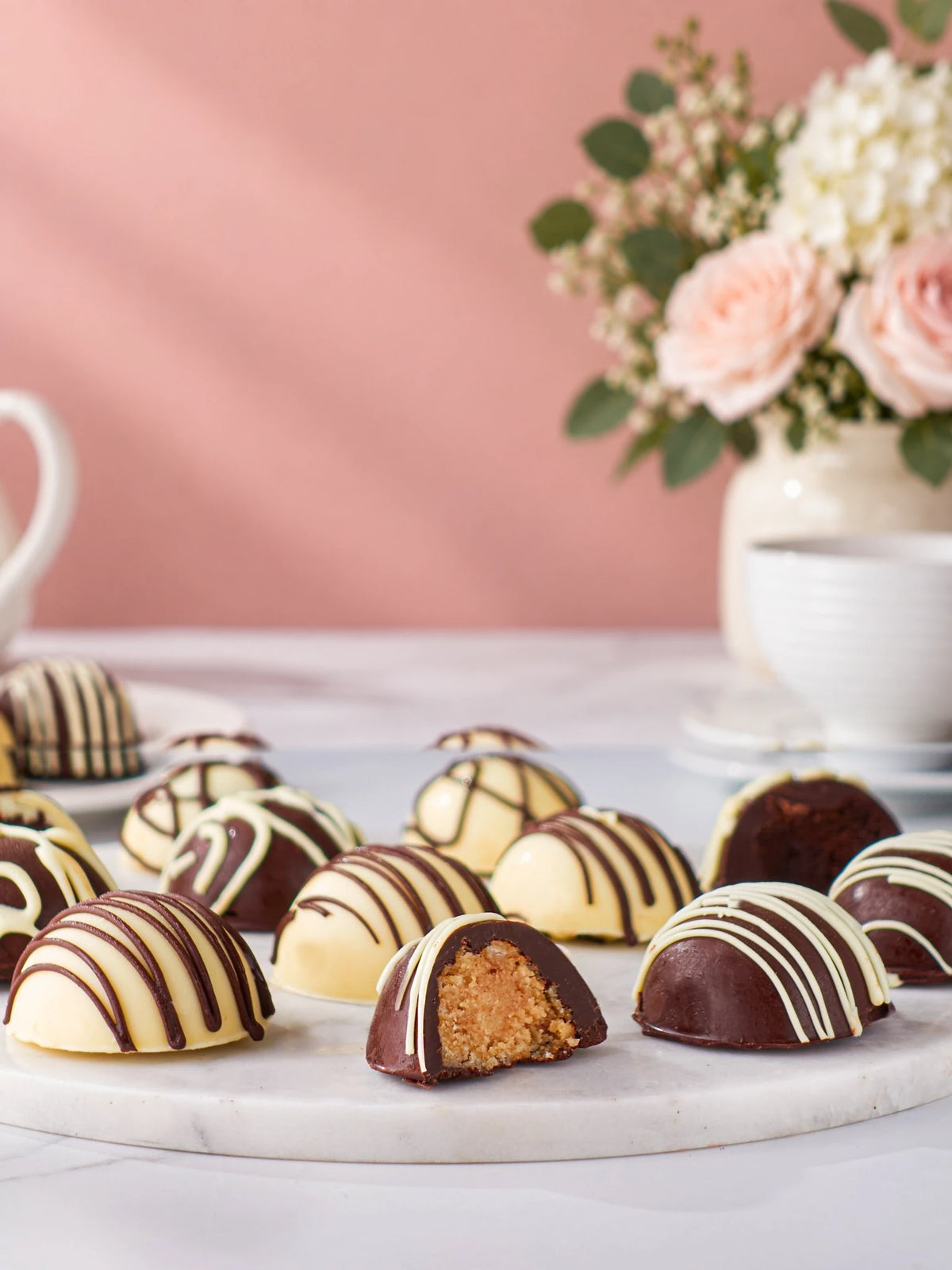 Chocolate-coated cake bites on a marble board, including a cut piece showing the centre by Patisserie Valerie