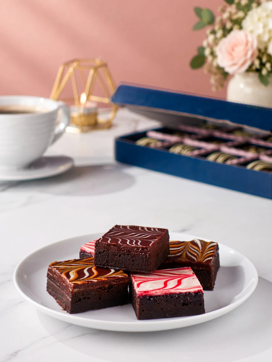 Chocolate brownies on a white plate with the open Happy Birthday gift box behind by Patisserie Valerie