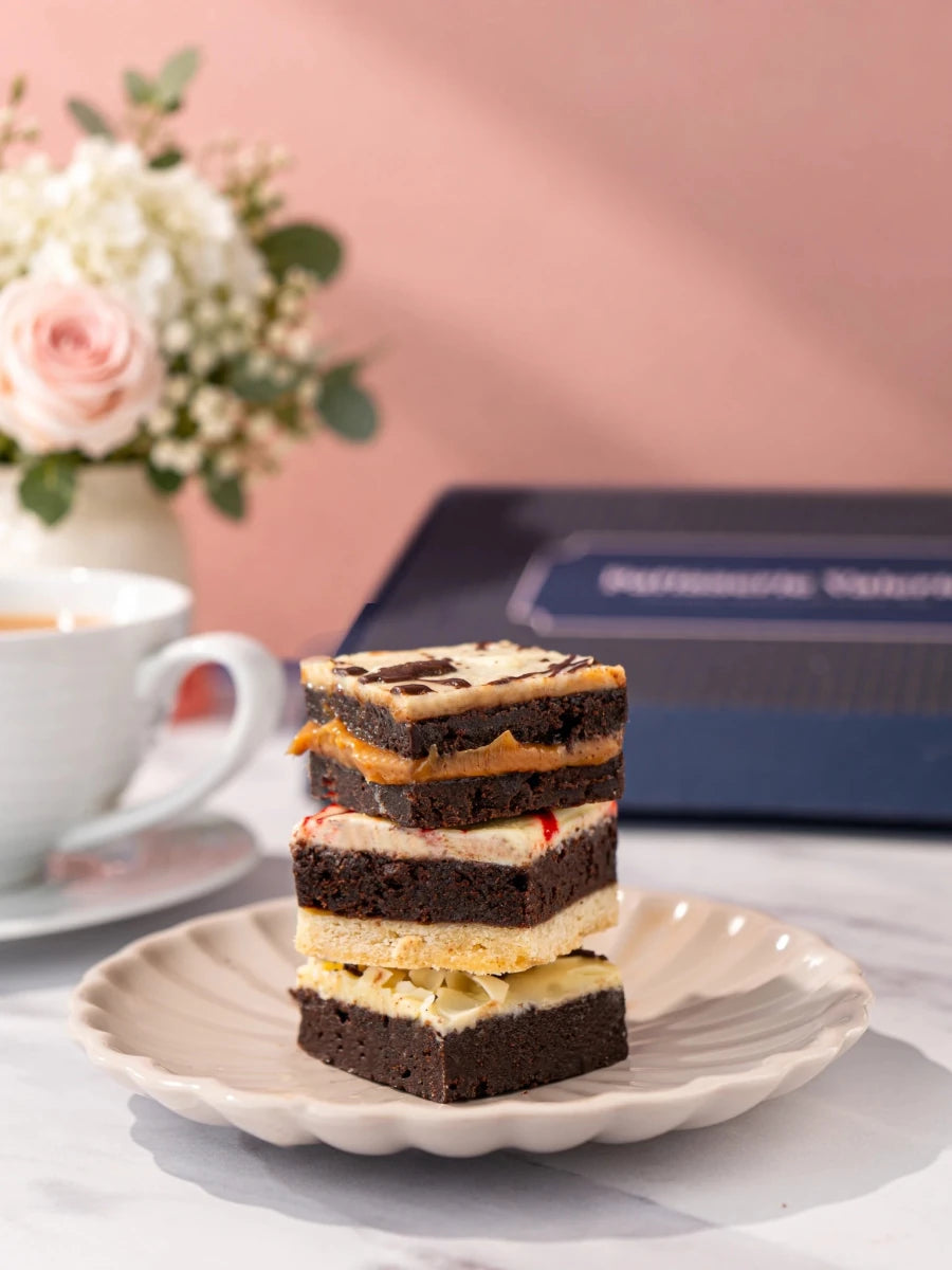 Three assorted luxury brownies stacked on a white plate by Patisserie Valerie