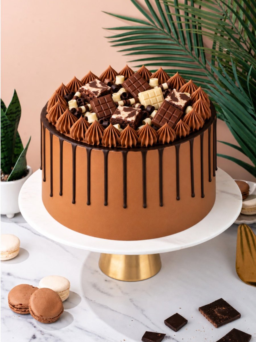 Indulgent Chocolate Celebration Cake on a white and gold cake stand on a marble table