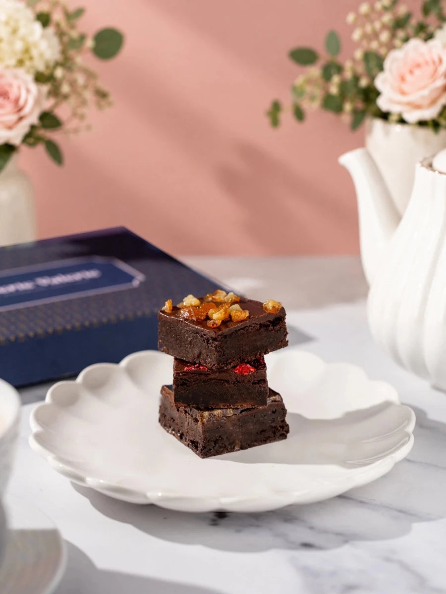 Three Kind Bakes vegan brownies stacked on a plate, with candied orange on top by Patisserie Valerie