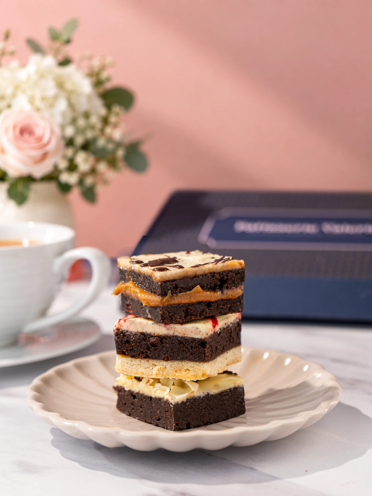 Three assorted luxury brownies stacked on a white plate by Patisserie Valerie