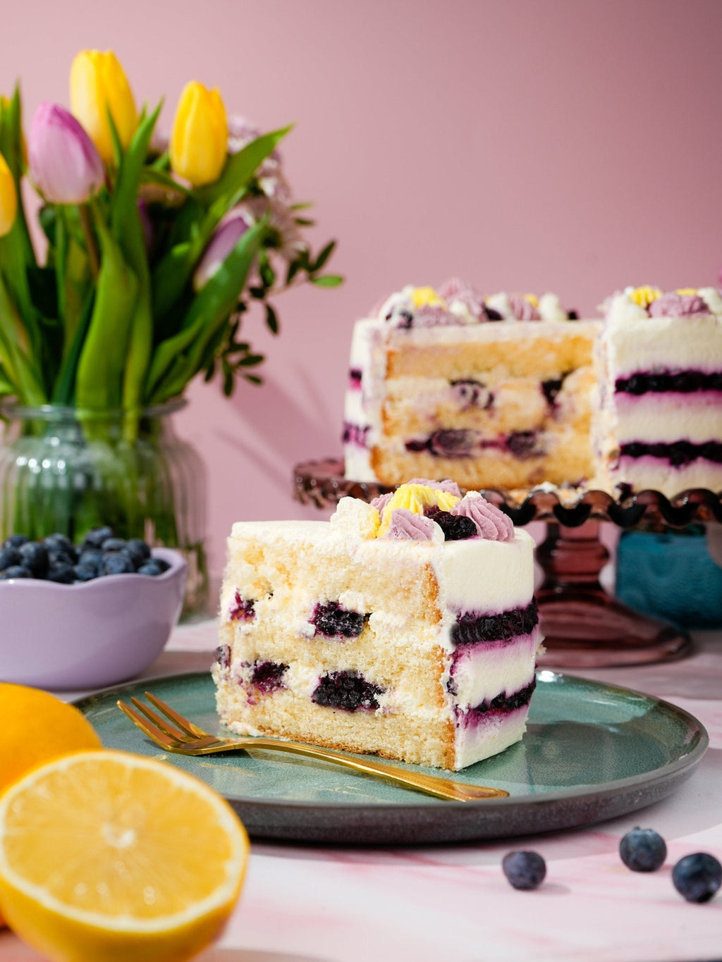 Patisserie Valerie's handmade Lemon & Blueberry Dream Cake being sliced to show blueberry compote layers