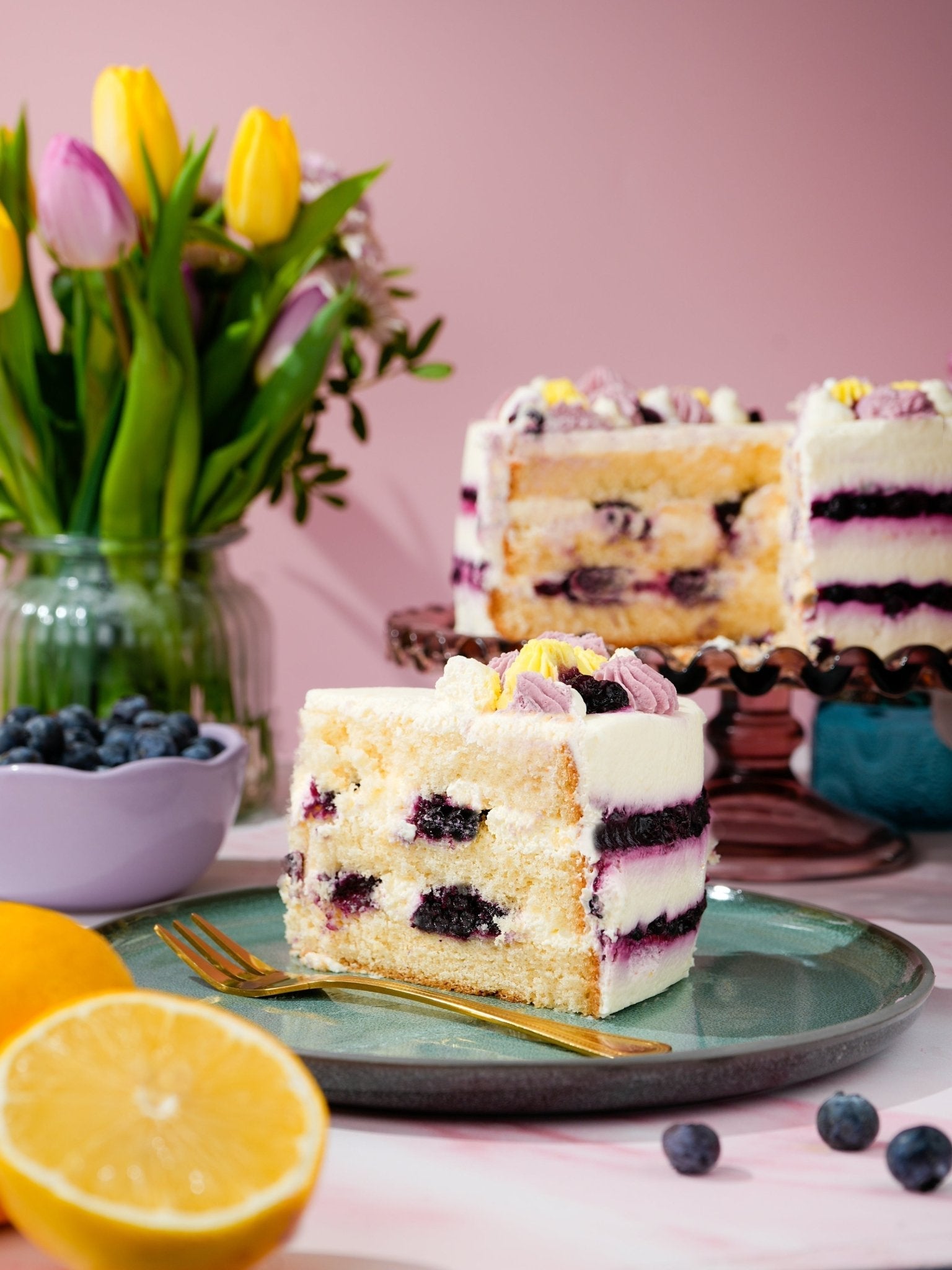 Patisserie Valerie's handmade Lemon & Blueberry Dream Cake being sliced to show blueberry compote layers