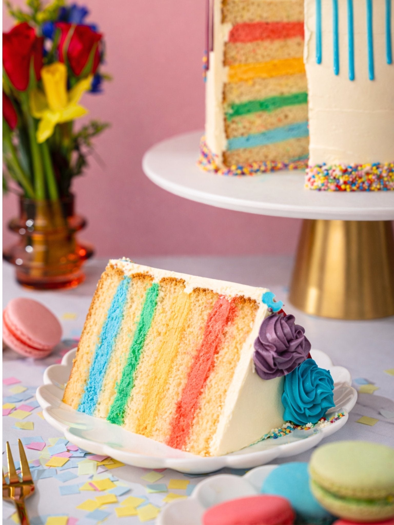 Patisserie Valerie's handmade Rainbow Cake with rainbow drips and swirls, sliced to reveal colourful layers