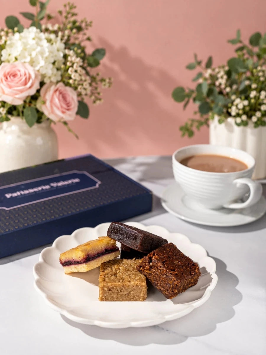 Four Old School Favourites traybakes on a plate beside the gift box by Patisserie Valerie
