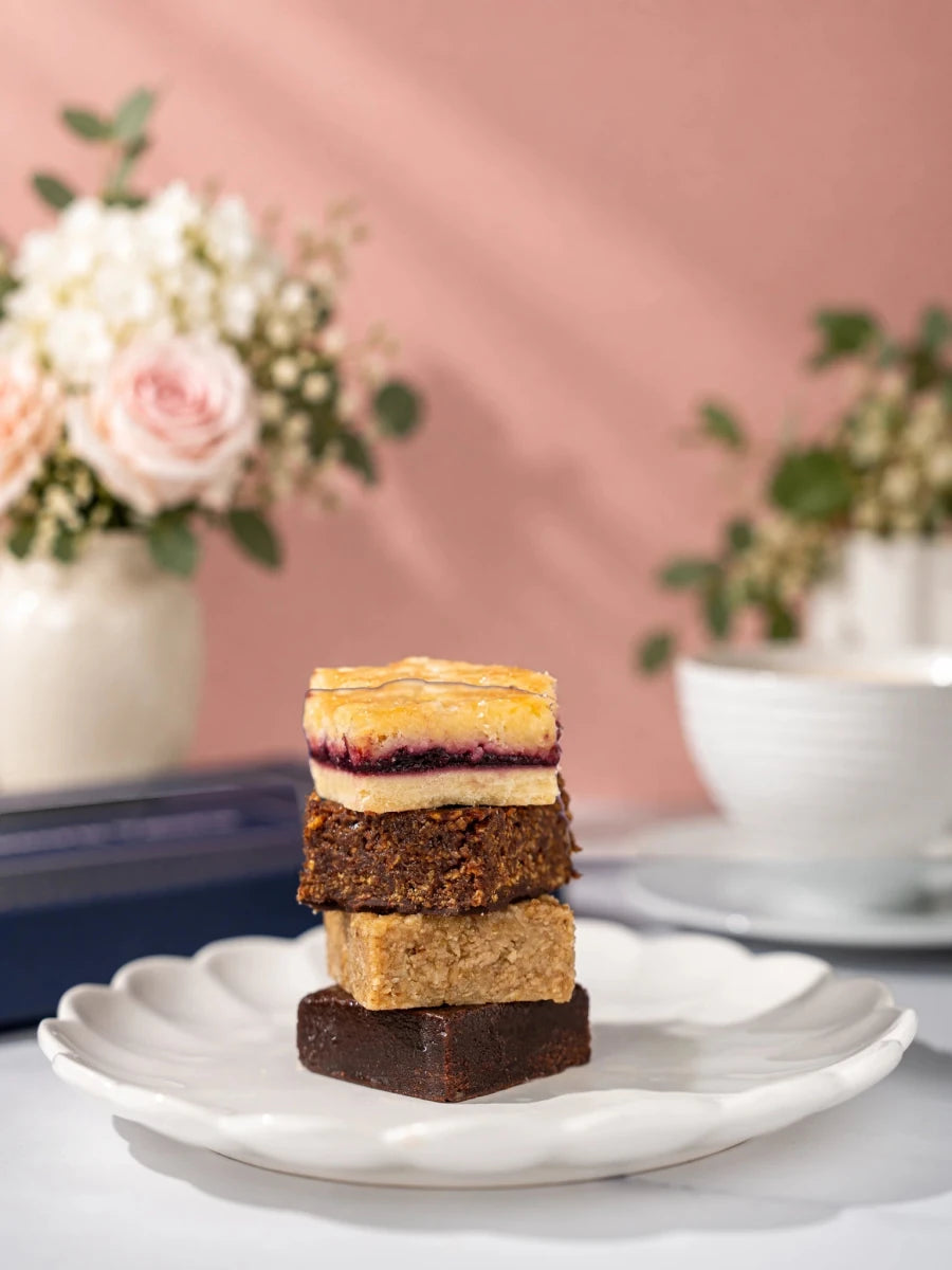 Four assorted Old School Favourites traybakes stacked on a white plate by Patisserie Valerie