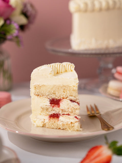Slice of vintage heart cake showing vanilla sponge with cream and raspberry between the layers